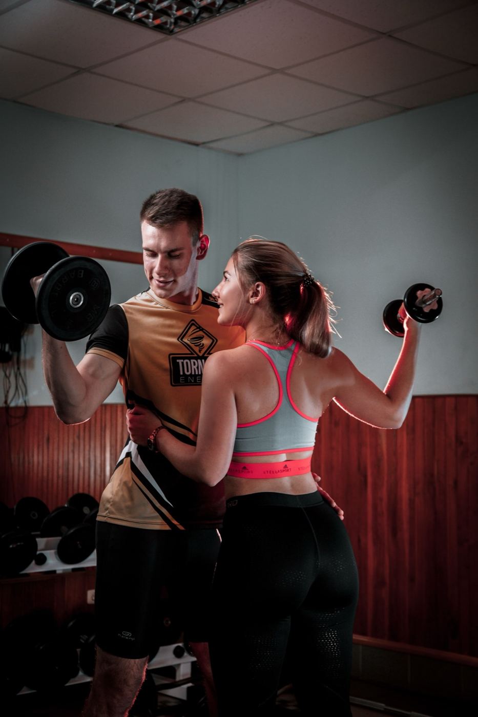 Couple lifting dumbbells side by side in a gym