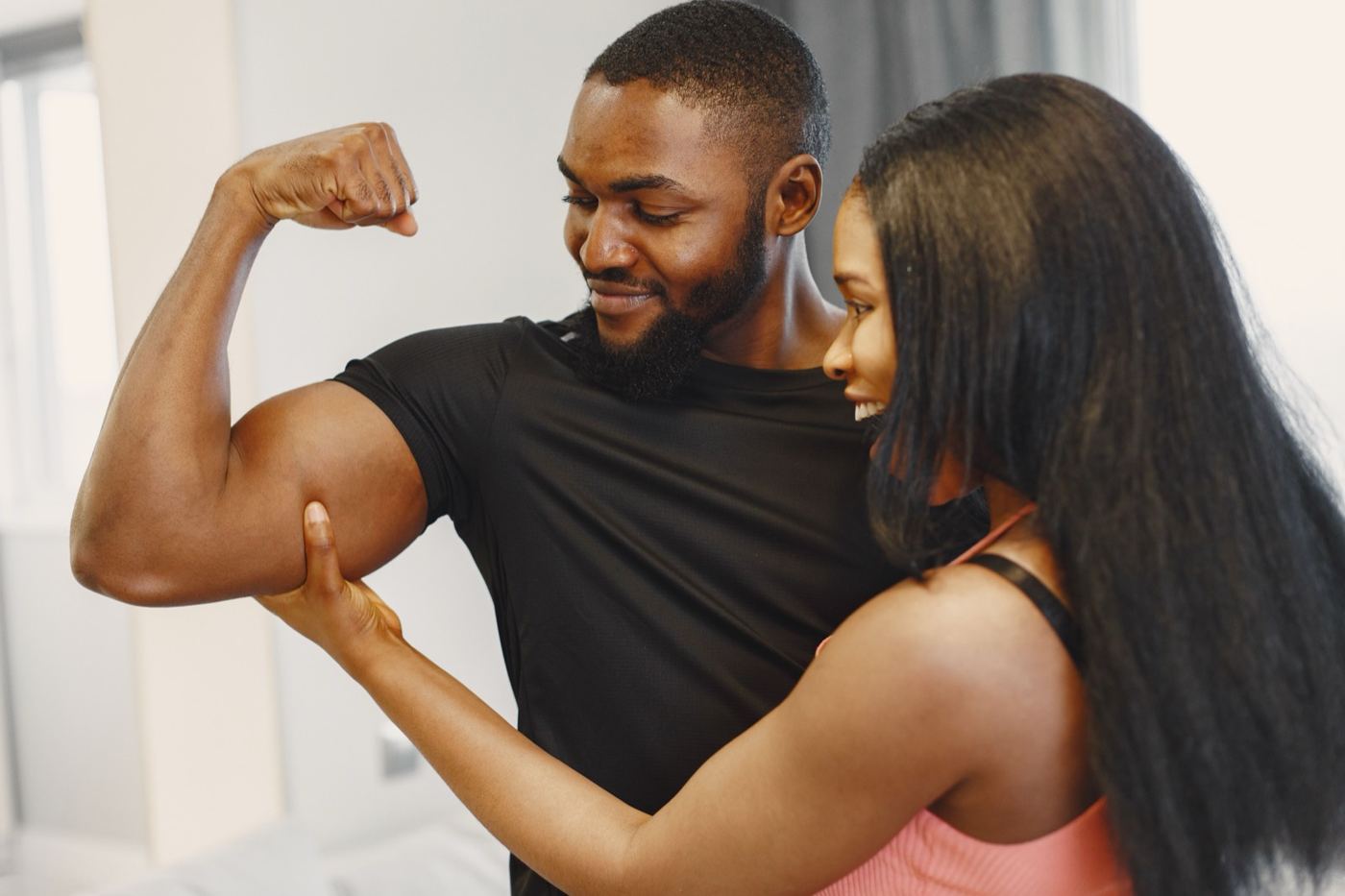 Smiling couple comparing biceps after a gym session