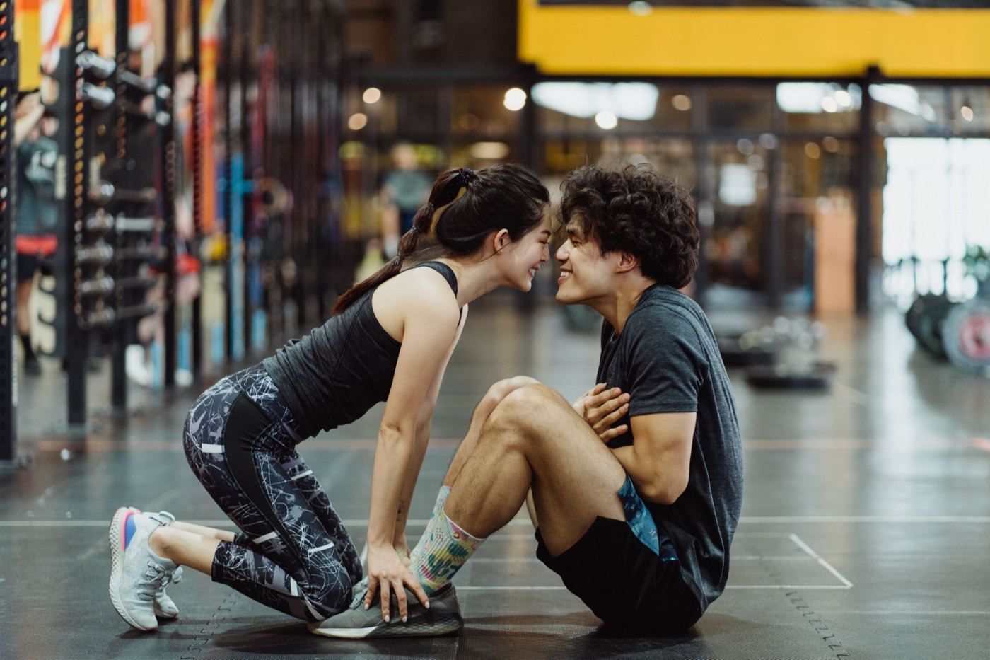 Couple stretching together on a gym floor