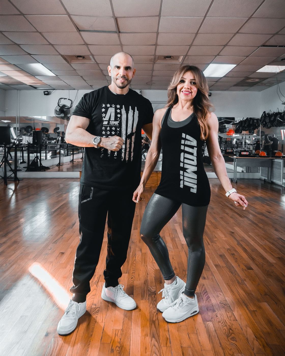 Woman and man posing together in a busy gym