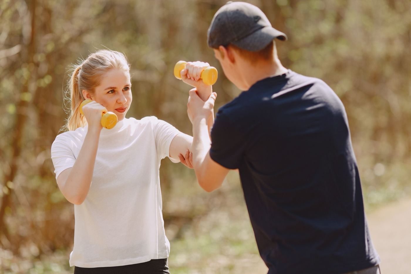 Couple training with light dumbbells in a sunny park