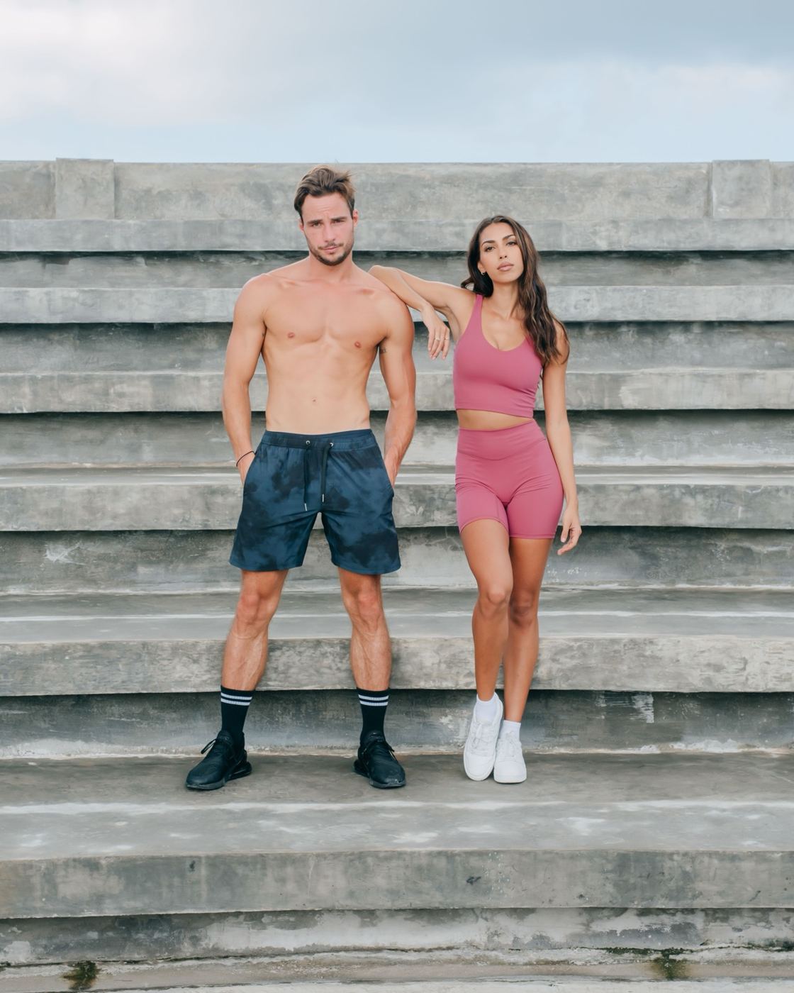 Couple in training gear standing on concrete stadium steps