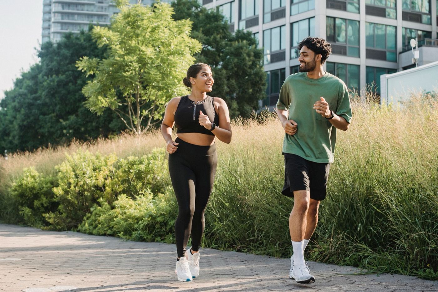 Man and woman jogging side by side along a city path