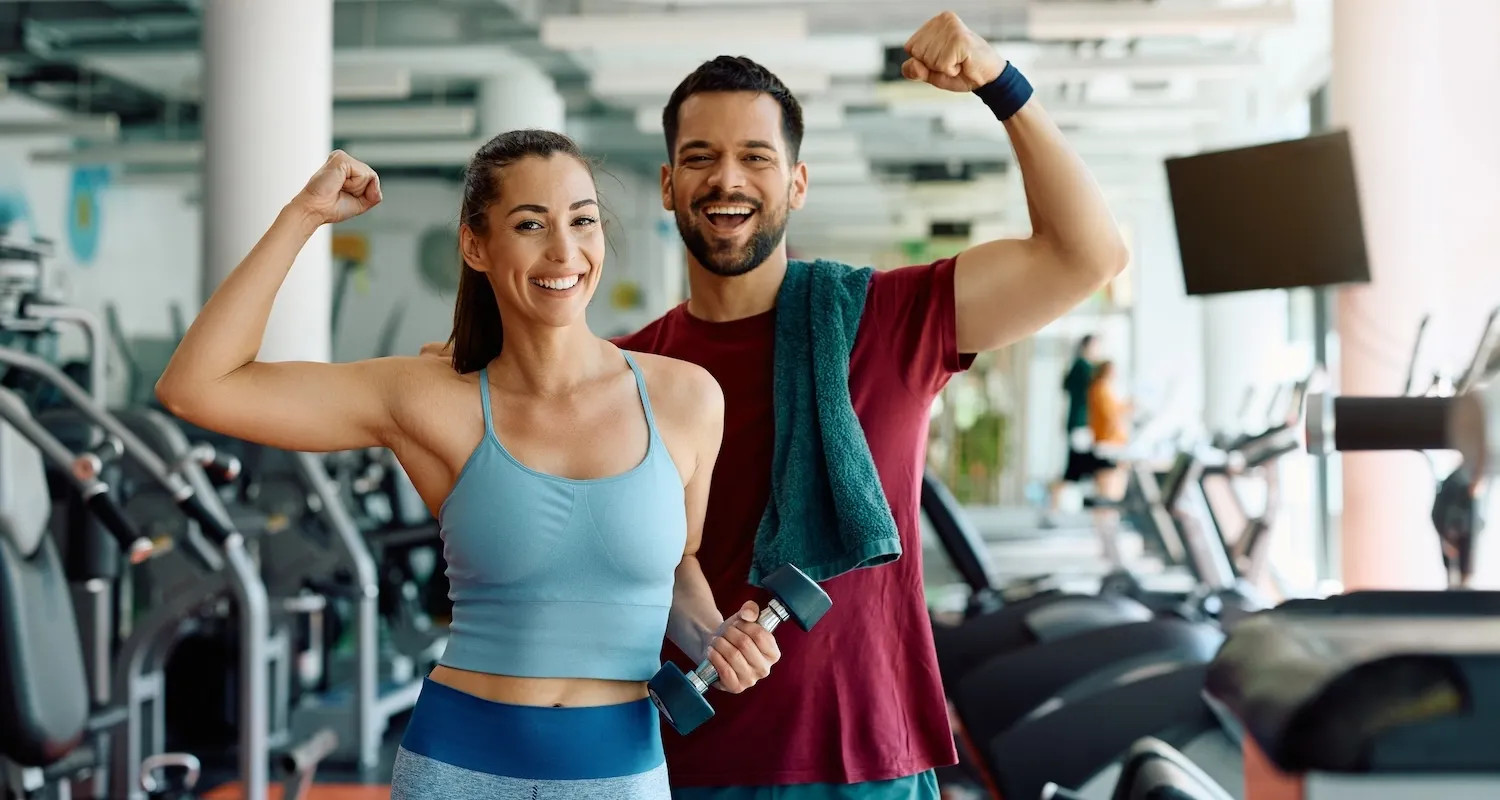 Two active singles smiling together in a gym after a workout